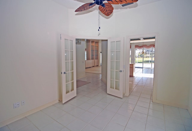 tiled empty room featuring ceiling fan, french doors, and a towering ceiling