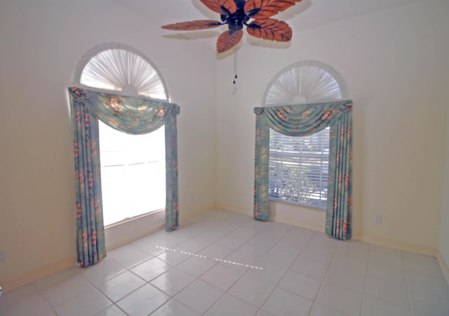 spare room with ceiling fan and light tile patterned floors