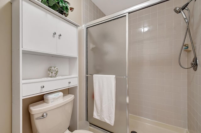 bathroom with toilet and a shower with door