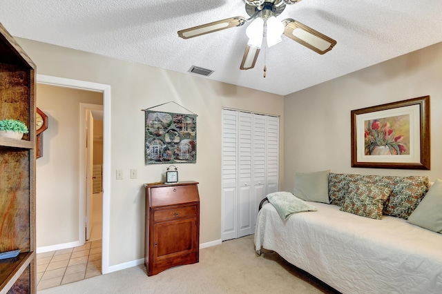 tiled bedroom with a textured ceiling, ceiling fan, and a closet