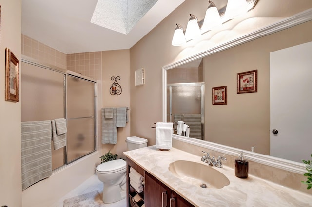 full bathroom featuring toilet, vanity, a skylight, and shower / bath combination with glass door