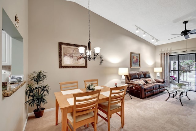 dining area featuring ceiling fan with notable chandelier, lofted ceiling, and light colored carpet