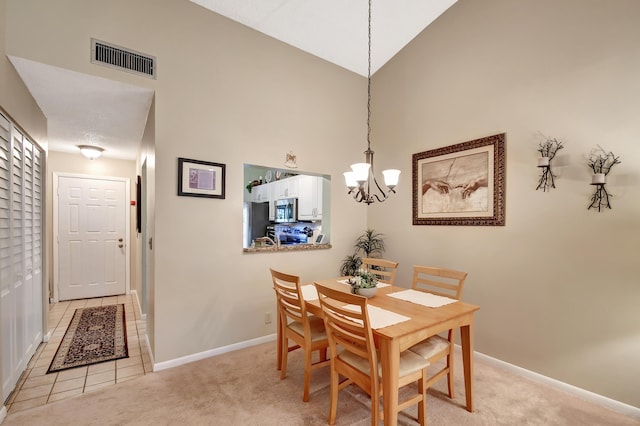 dining room featuring light colored carpet, high vaulted ceiling, and a notable chandelier