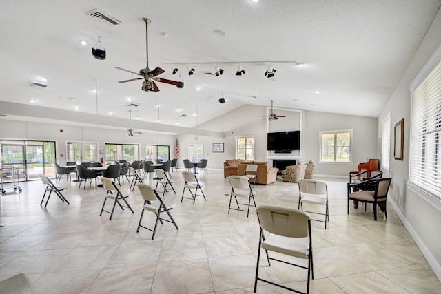 dining room with ceiling fan, plenty of natural light, light tile patterned flooring, and vaulted ceiling