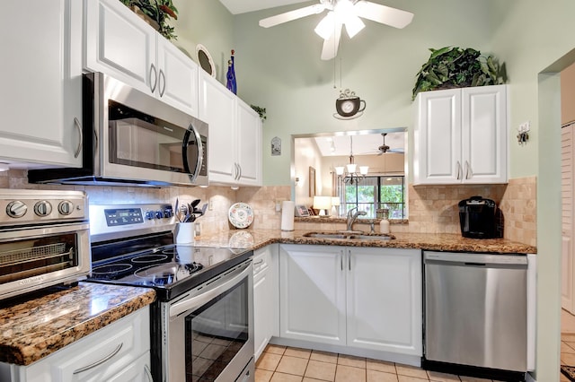 kitchen with stainless steel appliances, dark stone countertops, white cabinetry, and sink