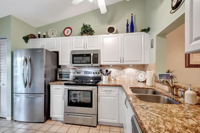 kitchen with appliances with stainless steel finishes, lofted ceiling, white cabinetry, sink, and light tile patterned floors