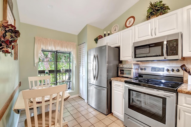 kitchen with light stone countertops, white cabinetry, appliances with stainless steel finishes, and light tile patterned flooring