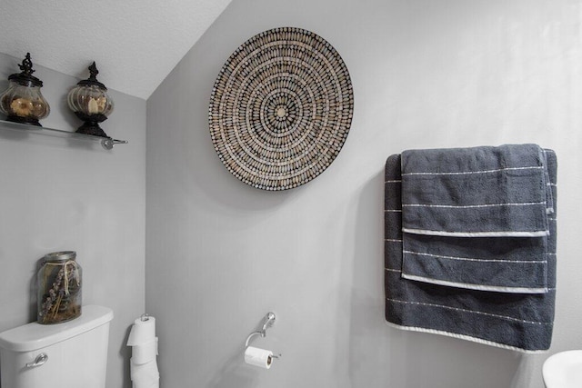 bathroom with a textured ceiling, toilet, and lofted ceiling