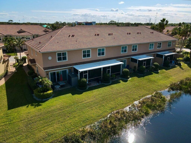 rear view of property featuring a water view, a yard, and a sunroom