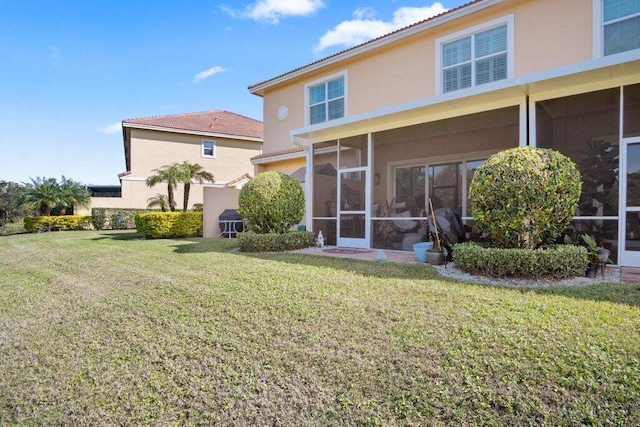 back of house with a sunroom and a lawn