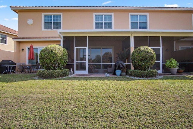 rear view of house featuring a sunroom and a lawn