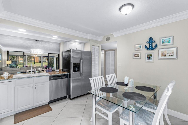 kitchen with light tile patterned floors, white cabinetry, stainless steel appliances, light stone countertops, and sink