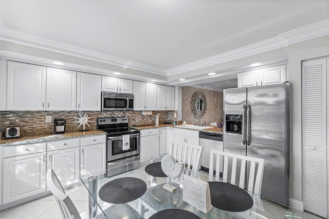 kitchen with light tile patterned floors, white cabinetry, stainless steel appliances, backsplash, and sink