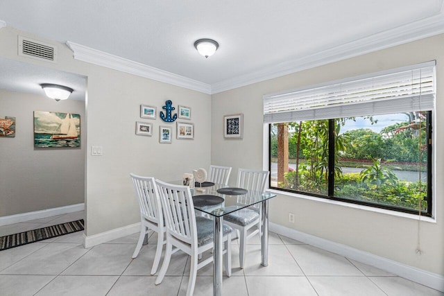 tiled dining space featuring a healthy amount of sunlight and crown molding