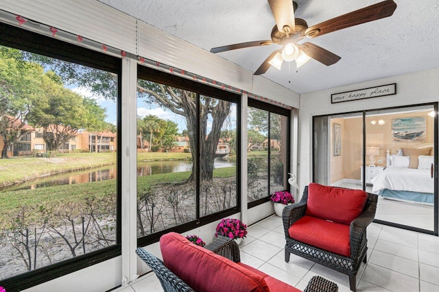 sunroom / solarium featuring a water view and ceiling fan