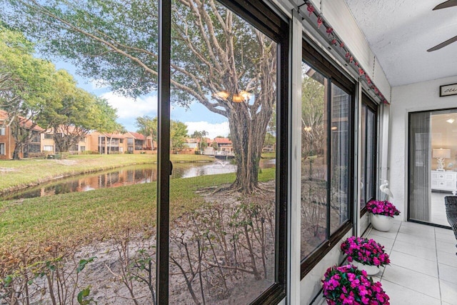 unfurnished sunroom with a water view and ceiling fan