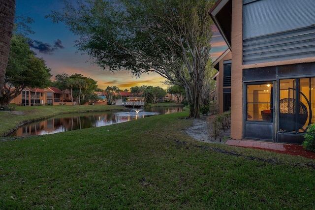 yard at dusk featuring a water view