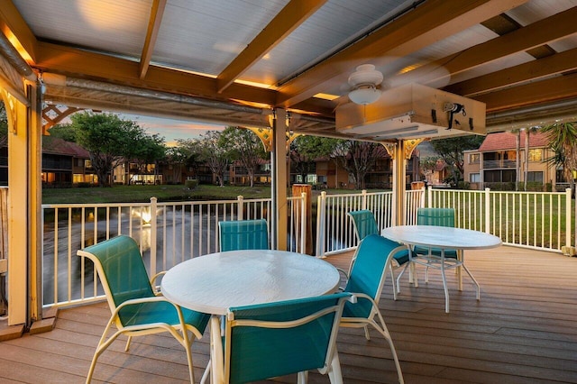 deck at dusk with ceiling fan and a yard