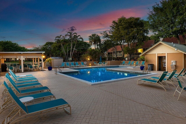 pool at dusk with a shed and a patio