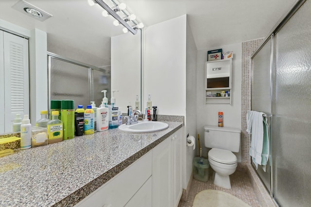 bathroom featuring toilet, tile patterned floors, an enclosed shower, and vanity