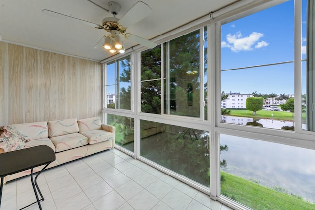 unfurnished sunroom featuring ceiling fan and a water view