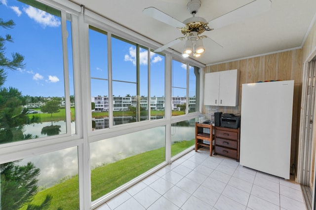 sunroom featuring ceiling fan and a water view