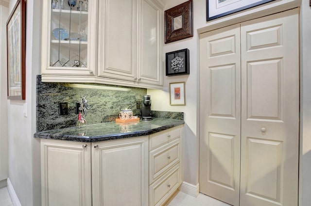 bar featuring light tile patterned flooring, dark stone countertops, and decorative backsplash