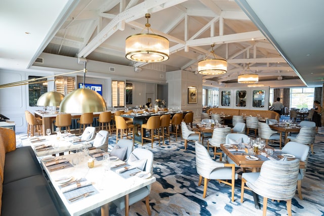 dining area featuring beam ceiling, carpet floors, and high vaulted ceiling