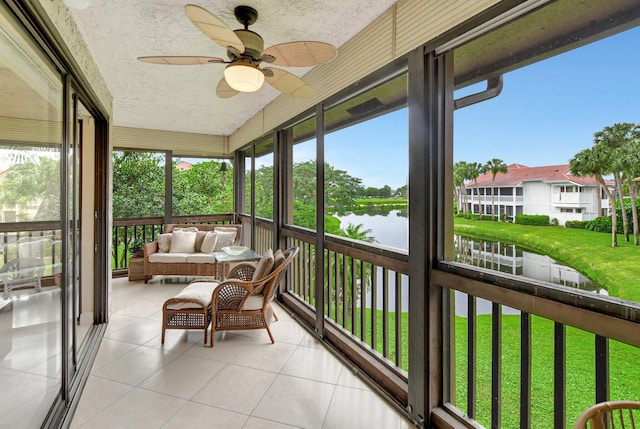 sunroom with ceiling fan and a water view