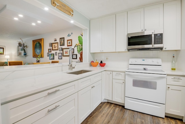 kitchen with electric stove, kitchen peninsula, sink, white cabinetry, and hardwood / wood-style flooring