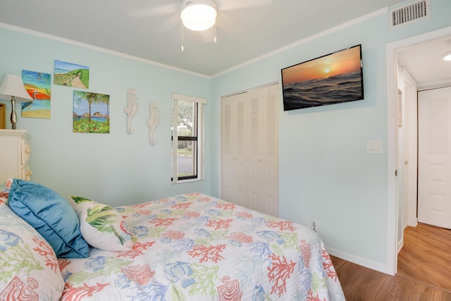 bedroom with a closet, crown molding, ceiling fan, and wood-type flooring