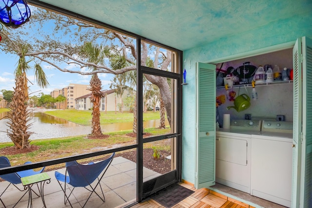 unfurnished sunroom featuring a water view and separate washer and dryer