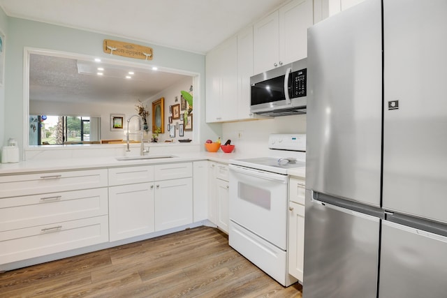 kitchen featuring white cabinetry, kitchen peninsula, light wood-type flooring, sink, and appliances with stainless steel finishes