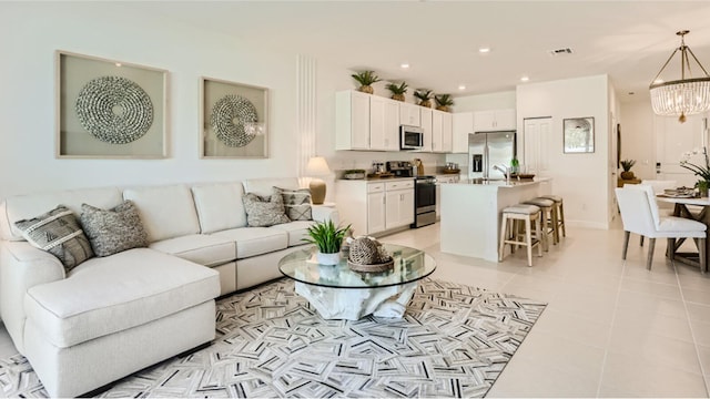 living room featuring sink, light tile patterned floors, and a chandelier