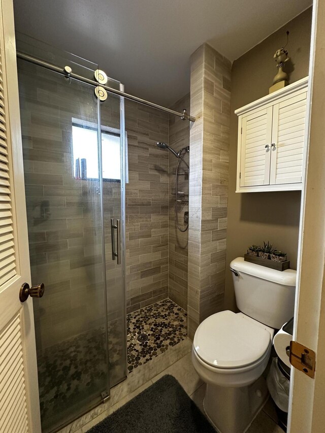 bathroom featuring a shower with shower door, tile patterned floors, toilet, and vanity