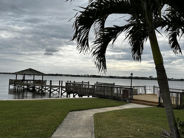 view of dock featuring a lawn and a water view