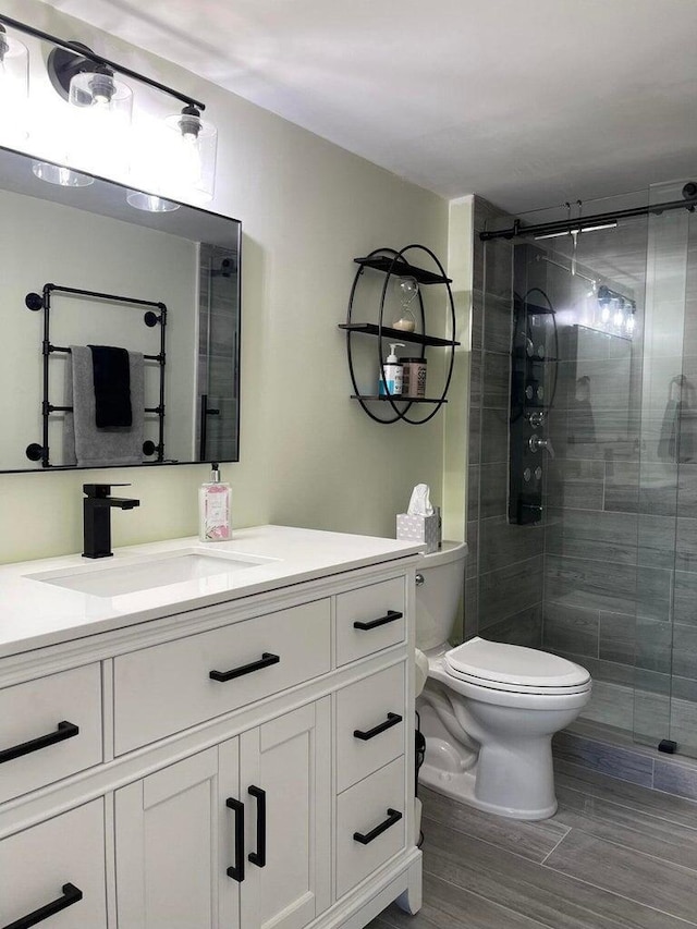 bathroom featuring toilet, a shower with shower door, and vanity