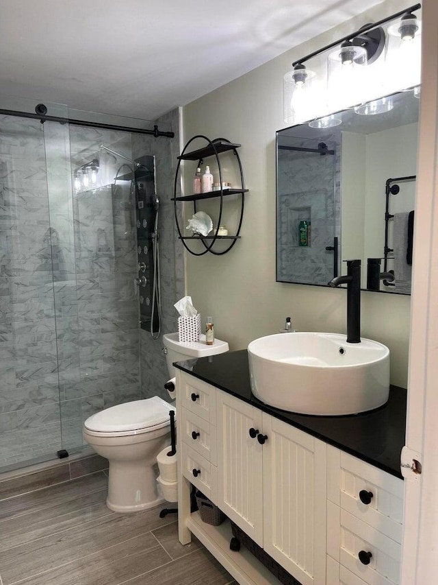 bathroom with toilet, vanity, and tiled shower