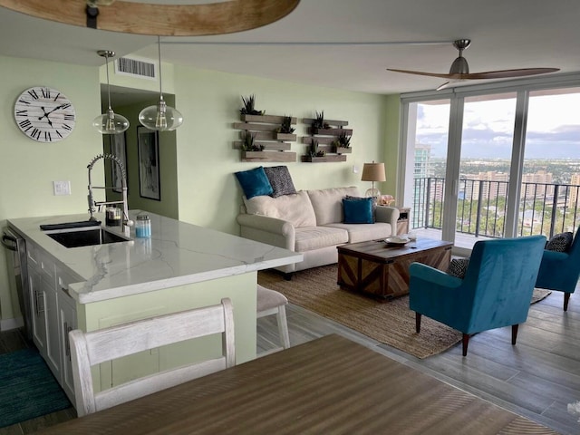 living room with hardwood / wood-style flooring, sink, expansive windows, and ceiling fan