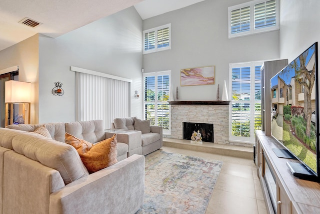 living room featuring light tile patterned floors, plenty of natural light, a fireplace, and a high ceiling