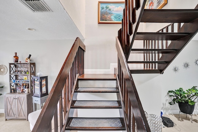 staircase featuring tile patterned flooring and a textured ceiling