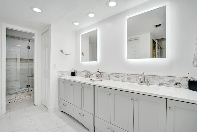 bathroom featuring vanity, a shower with shower door, a textured ceiling, and backsplash