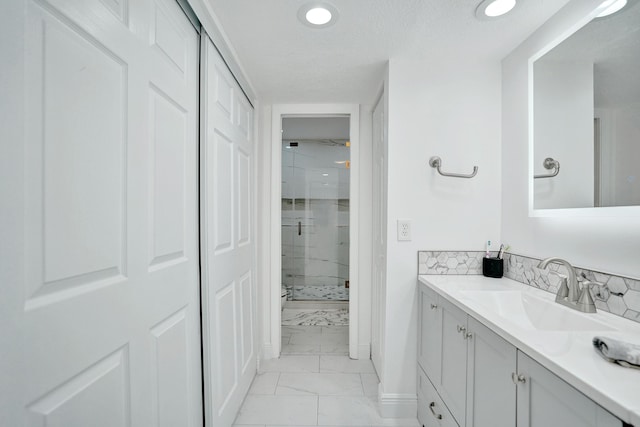 bathroom featuring vanity, a shower with door, and a textured ceiling