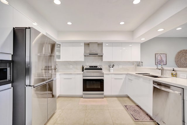 kitchen with sink, stainless steel appliances, tasteful backsplash, white cabinets, and wall chimney exhaust hood