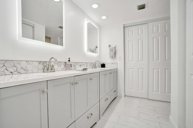 bathroom featuring decorative backsplash, vanity, and a textured ceiling