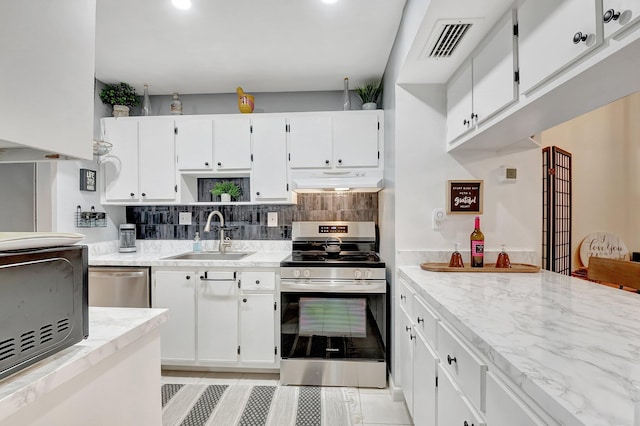 kitchen featuring sink, light tile patterned floors, white cabinetry, stainless steel appliances, and light stone counters