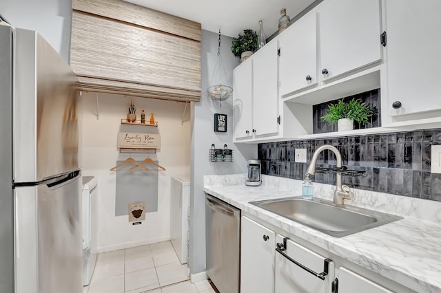 kitchen featuring sink, white cabinets, backsplash, light tile patterned floors, and stainless steel appliances