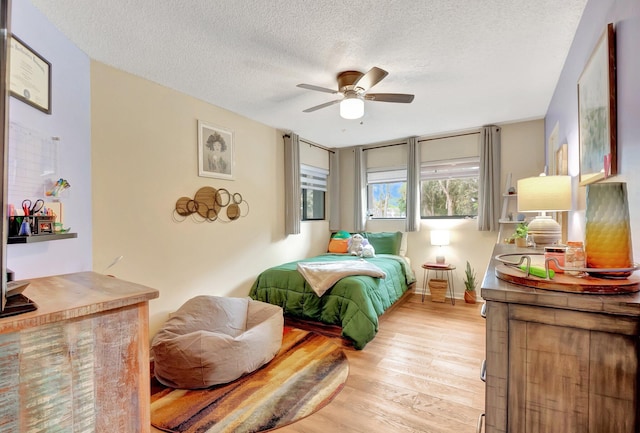 bedroom featuring a textured ceiling, light hardwood / wood-style flooring, and ceiling fan