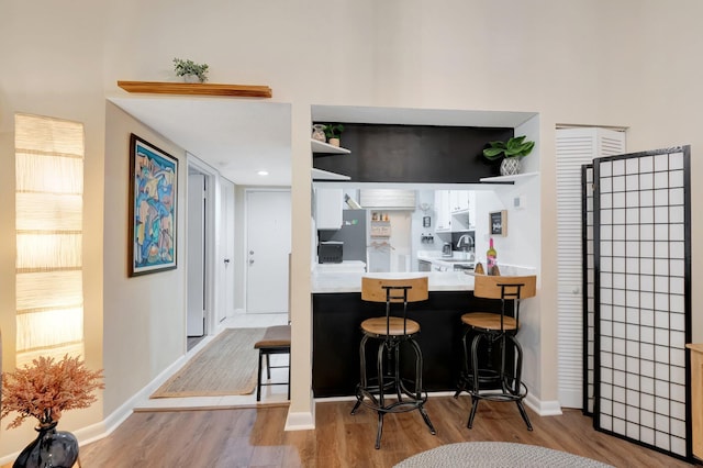 kitchen featuring a breakfast bar area, light hardwood / wood-style flooring, and stove