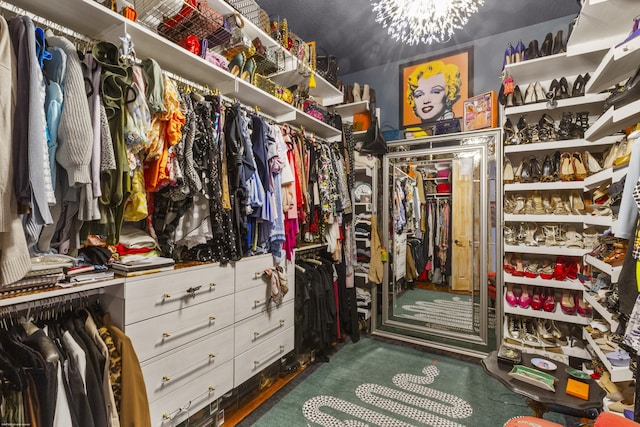 walk in closet featuring an inviting chandelier and dark carpet